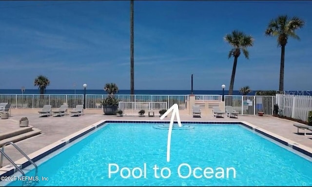 community pool featuring a water view, a patio area, and fence