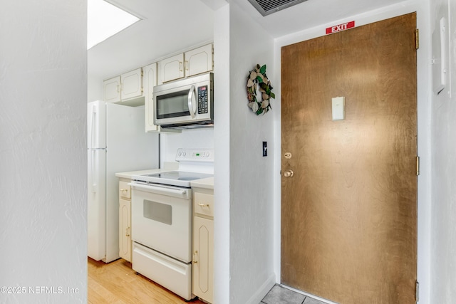 kitchen with white appliances, visible vents, light countertops, light wood-style floors, and white cabinetry