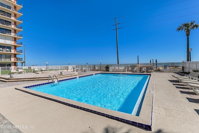 community pool with a patio area and fence