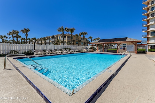 pool featuring an outbuilding, a patio area, and fence