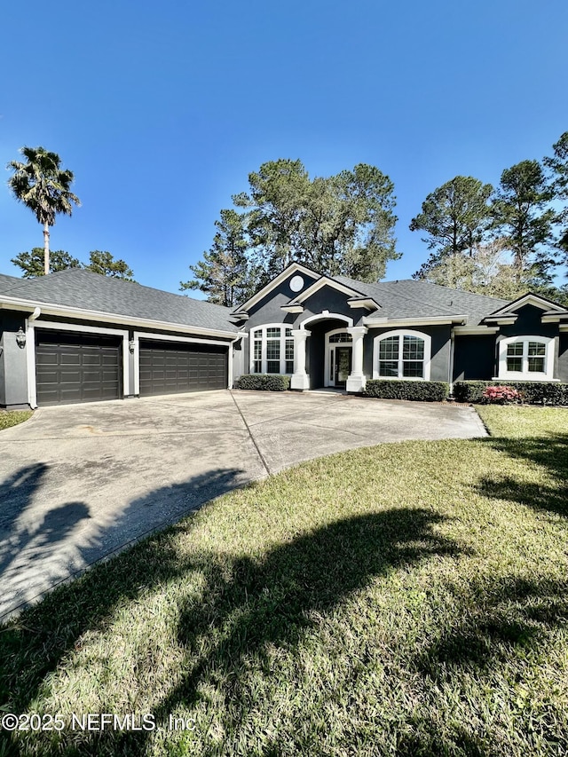 ranch-style house featuring a garage, a front yard, concrete driveway, and stucco siding