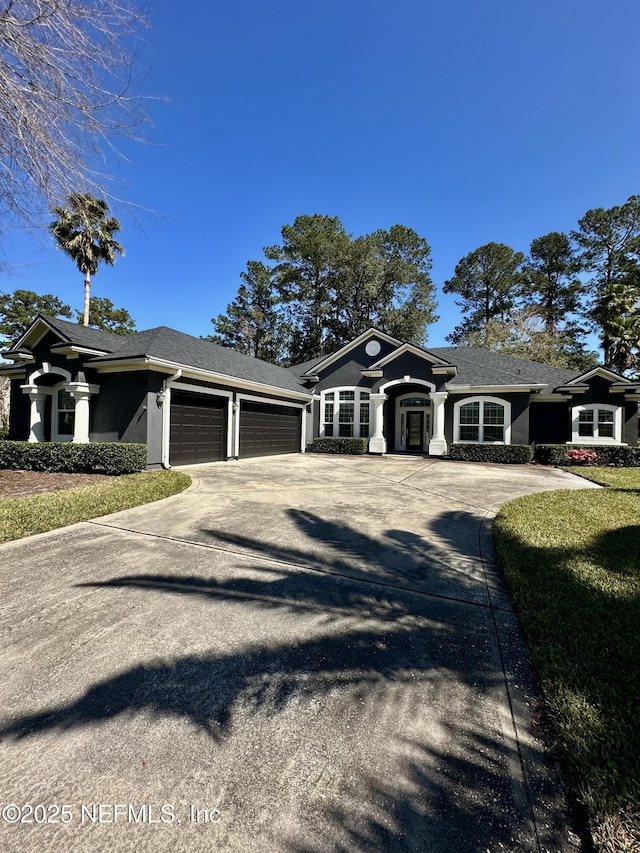 view of front of property with a garage, a front yard, concrete driveway, and stucco siding