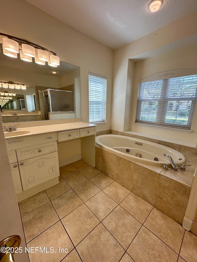 full bath featuring a stall shower, a jetted tub, tile patterned flooring, a textured ceiling, and vanity