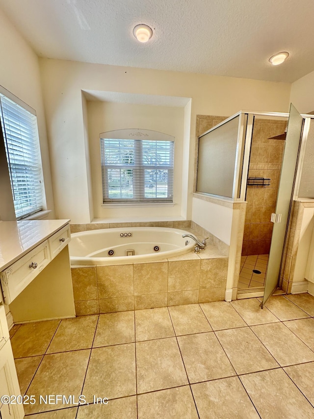 bathroom featuring vanity, a shower stall, a textured ceiling, tile patterned flooring, and a jetted tub