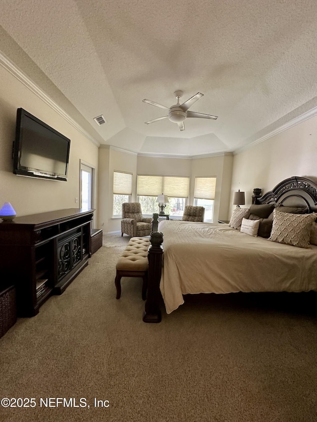 carpeted bedroom with a raised ceiling, visible vents, ornamental molding, ceiling fan, and a textured ceiling