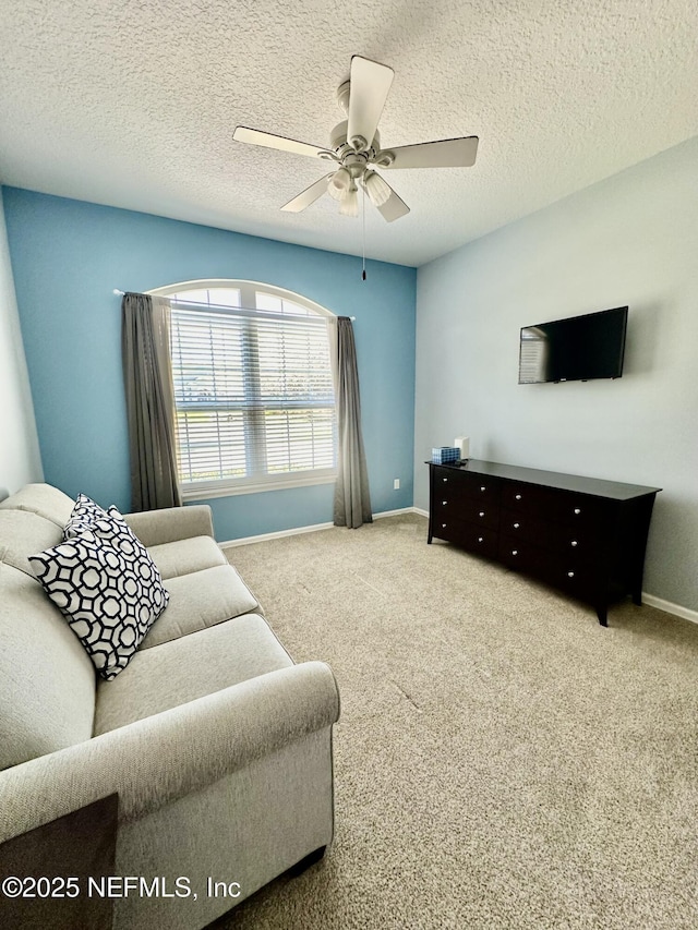 carpeted living room featuring ceiling fan, a textured ceiling, and baseboards