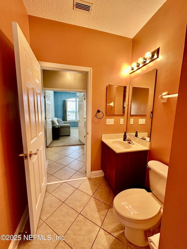 bathroom with a textured ceiling, tile patterned flooring, toilet, vanity, and visible vents