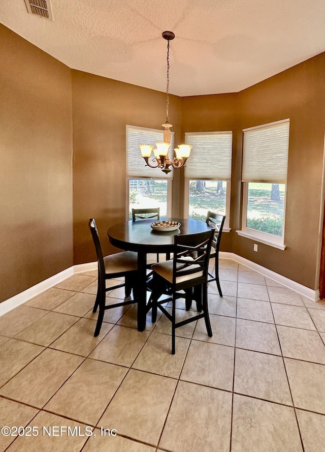 dining room with a chandelier, light tile patterned flooring, visible vents, and baseboards