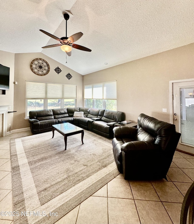 living room featuring lofted ceiling, ceiling fan, a textured ceiling, and light tile patterned floors