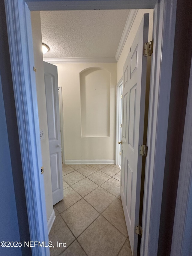 hall featuring ornamental molding, tile patterned flooring, a textured ceiling, and baseboards