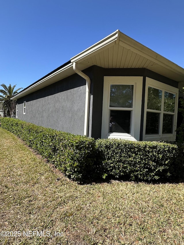 view of side of home featuring a yard and stucco siding