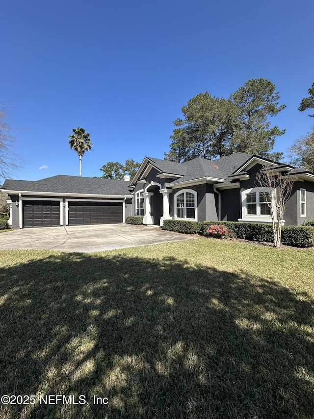 view of front facade with an attached garage, a front lawn, concrete driveway, and stucco siding