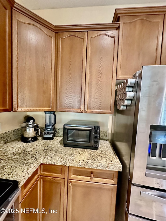 kitchen with a toaster, light stone counters, and stainless steel appliances