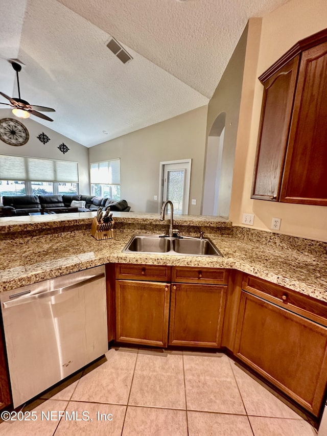 kitchen with light stone counters, lofted ceiling, visible vents, stainless steel dishwasher, and a sink