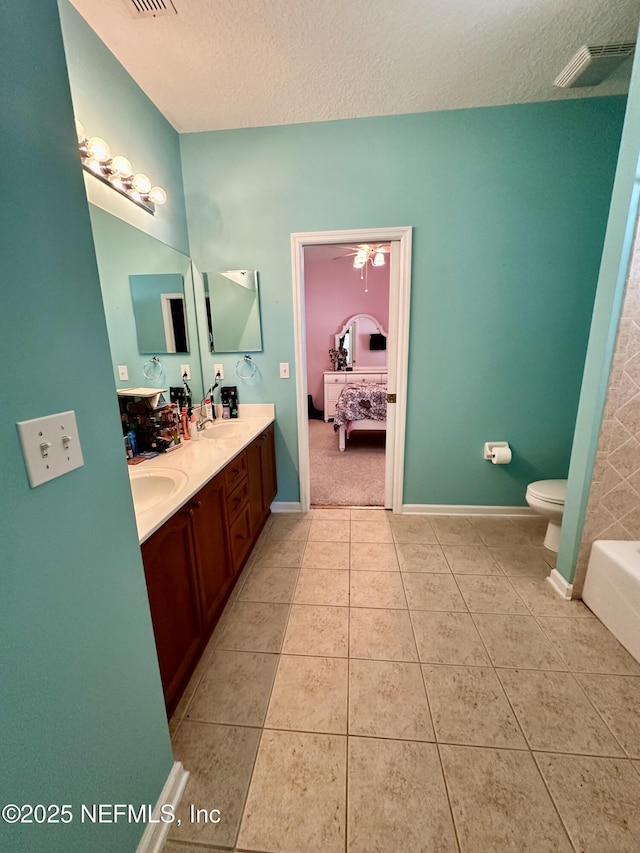 bathroom featuring toilet, a sink, visible vents, tile patterned floors, and double vanity