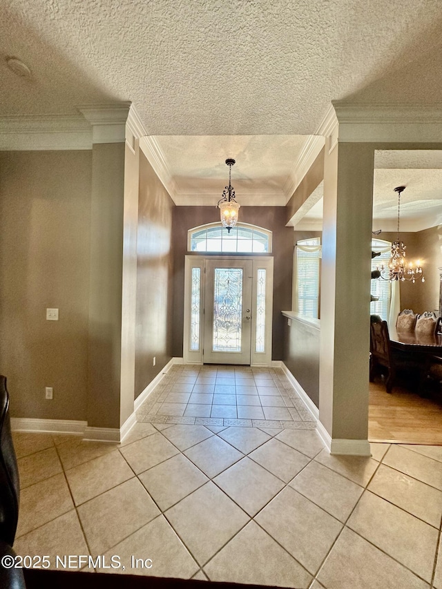 foyer featuring a chandelier, light tile patterned floors, a textured ceiling, and ornamental molding