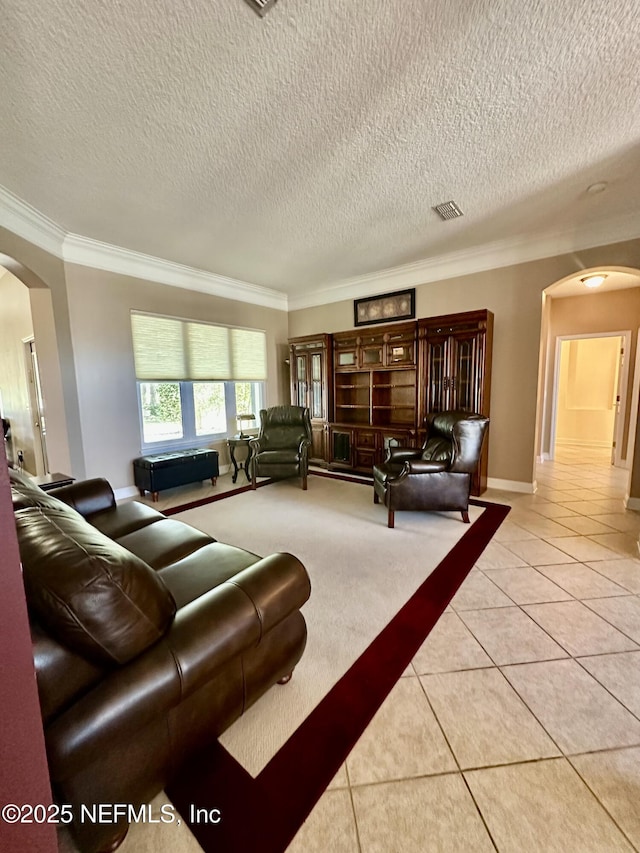 living area featuring light tile patterned floors, visible vents, arched walkways, baseboards, and crown molding