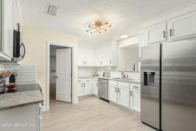 kitchen featuring appliances with stainless steel finishes, light wood-type flooring, visible vents, and white cabinetry