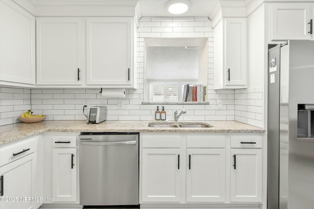 kitchen with a sink, light stone countertops, stainless steel appliances, white cabinetry, and backsplash