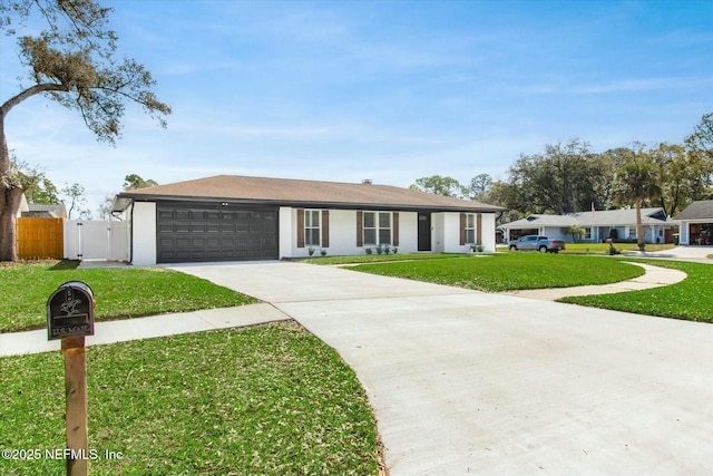 ranch-style home with concrete driveway, an attached garage, a gate, fence, and a front lawn