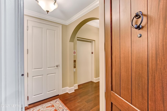 entryway featuring arched walkways, ornamental molding, dark wood-style floors, and baseboards