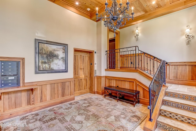 stairs featuring wood ceiling, a wainscoted wall, a notable chandelier, and a high ceiling