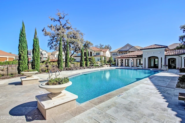 community pool with a residential view, a patio, and fence