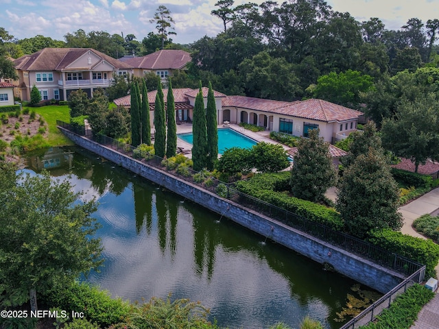 back of property featuring a fenced in pool, a water view, fence, and a tiled roof