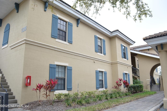 view of side of home with stairs and stucco siding