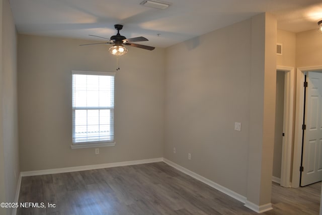 spare room with ceiling fan, wood finished floors, visible vents, and baseboards