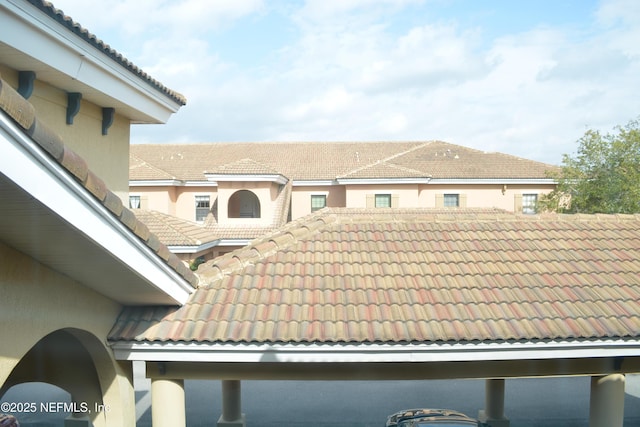 exterior space featuring stucco siding and a tiled roof