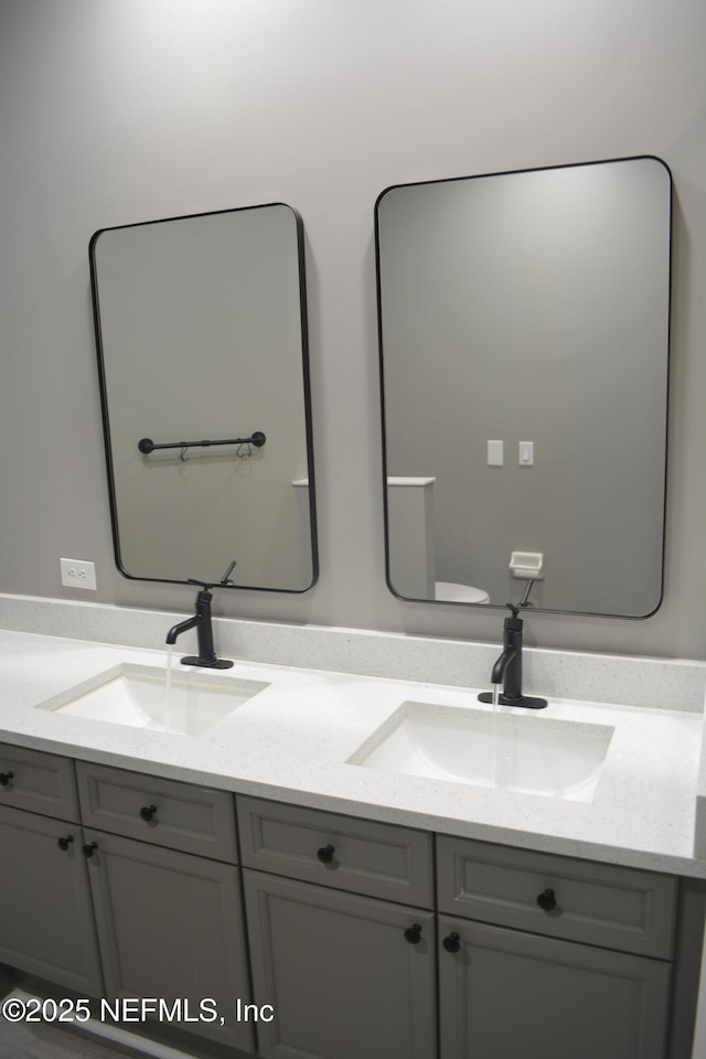 bathroom with double vanity, toilet, and a sink