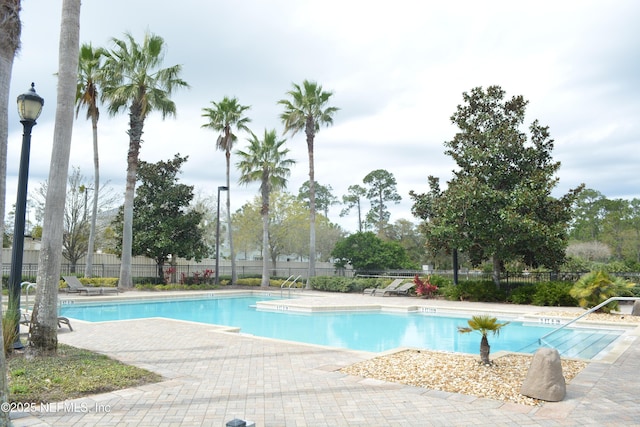 community pool with a patio and fence