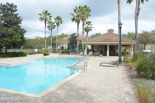 community pool with a patio and fence