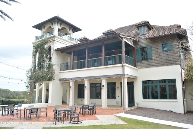 back of property with a balcony, a patio area, a tile roof, and stucco siding