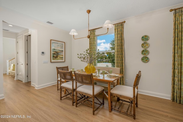 dining area with light wood-style floors, baseboards, and visible vents