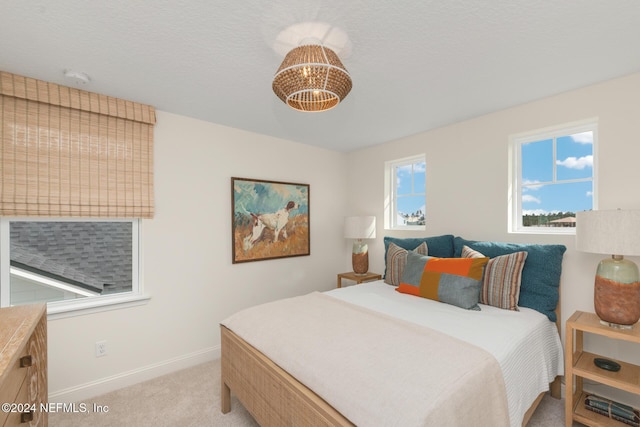 bedroom featuring a chandelier, light colored carpet, and baseboards