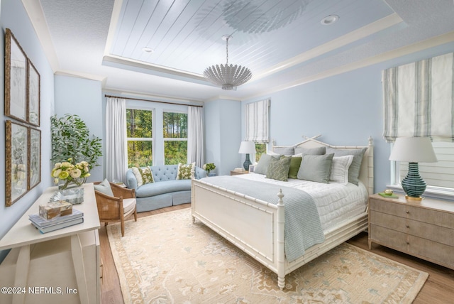 bedroom with a chandelier, a tray ceiling, and wood finished floors