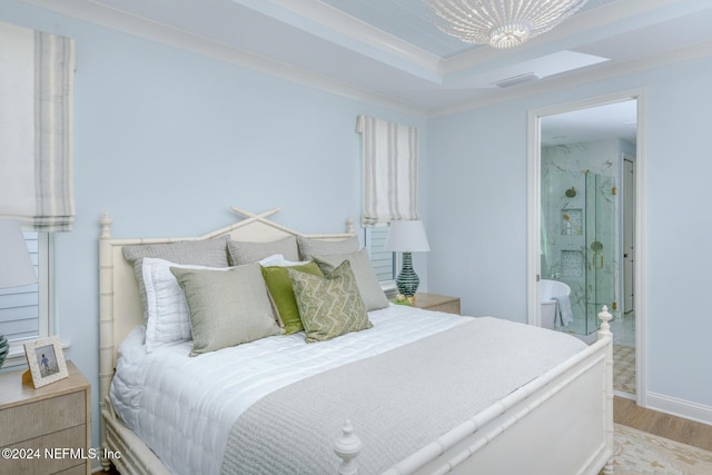 bedroom featuring a tray ceiling, visible vents, ensuite bath, wood finished floors, and baseboards