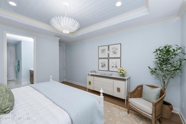 bedroom with baseboards, a tray ceiling, a chandelier, and wood finished floors