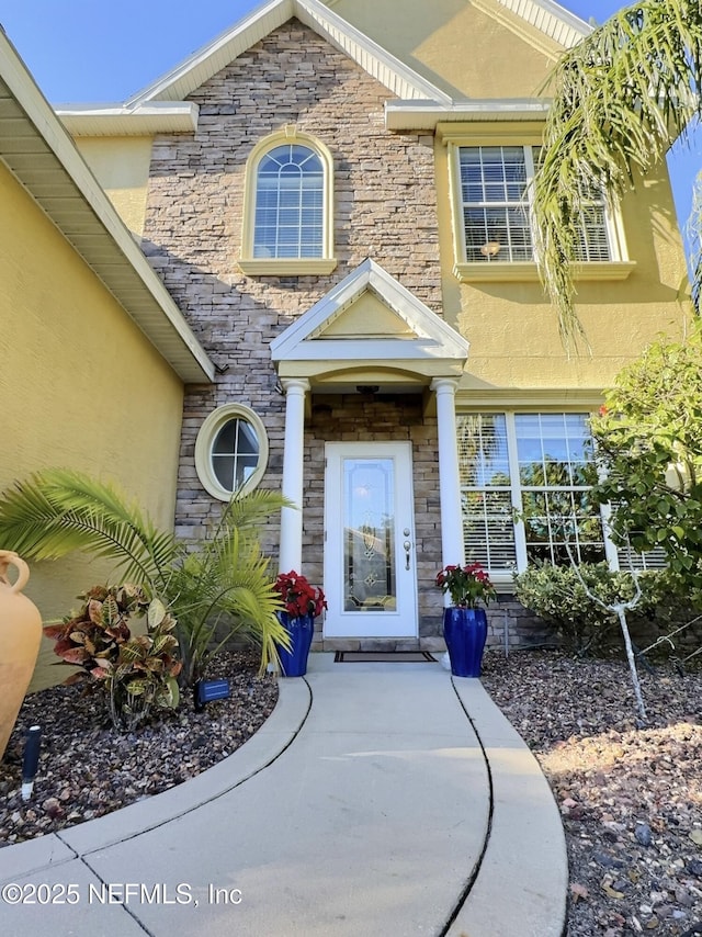 property entrance with stone siding and stucco siding