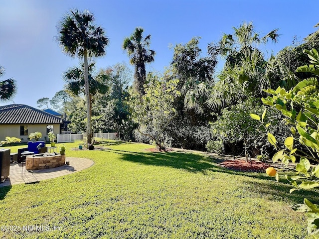 view of yard with fence, a fire pit, and a patio