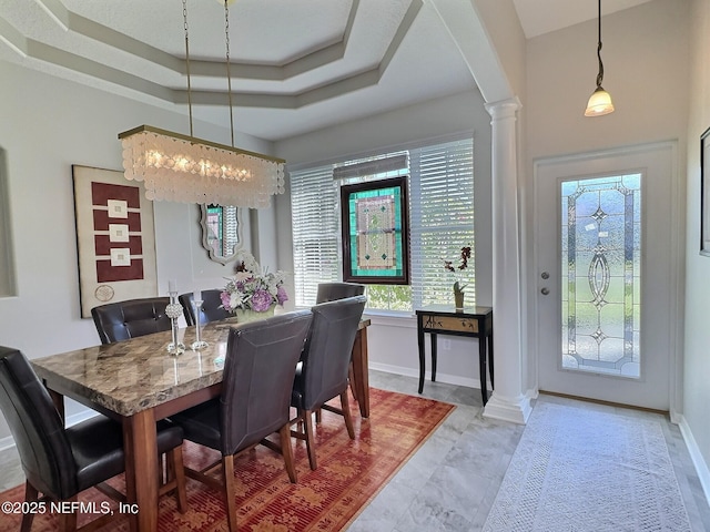 dining space featuring decorative columns, baseboards, a raised ceiling, and arched walkways