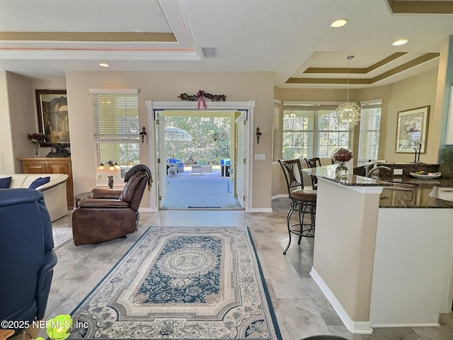 entryway with plenty of natural light, a raised ceiling, visible vents, and baseboards