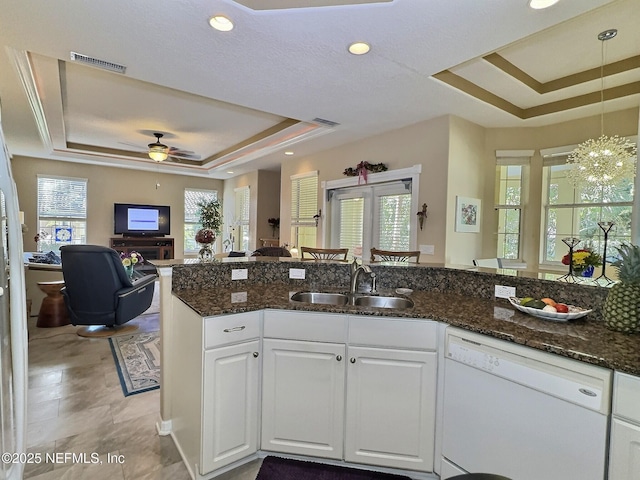 kitchen with a raised ceiling, visible vents, open floor plan, a sink, and dishwasher