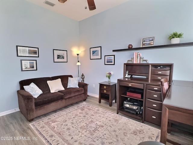 living room featuring a ceiling fan, baseboards, visible vents, and wood finished floors