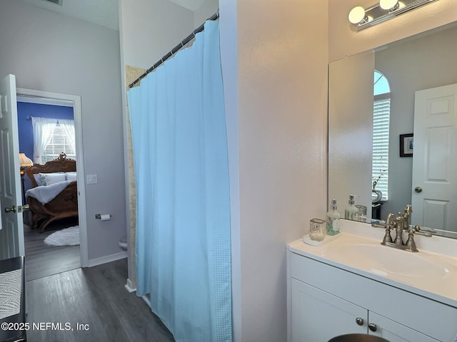 bathroom with toilet, vanity, ensuite bathroom, and wood finished floors