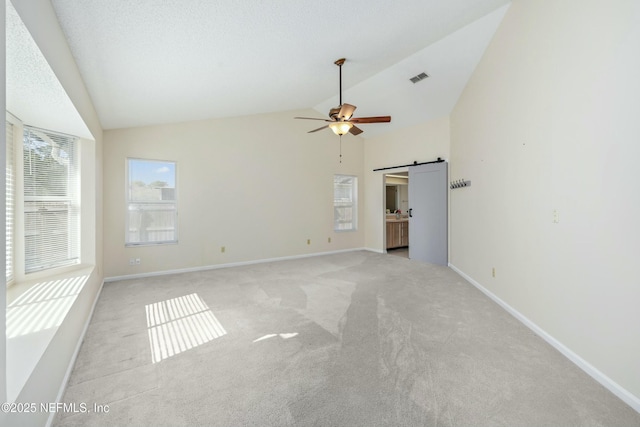 unfurnished room featuring a barn door, visible vents, ceiling fan, and baseboards