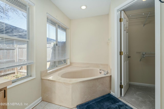 full bathroom with a spacious closet, baseboards, a bath, and tile patterned floors