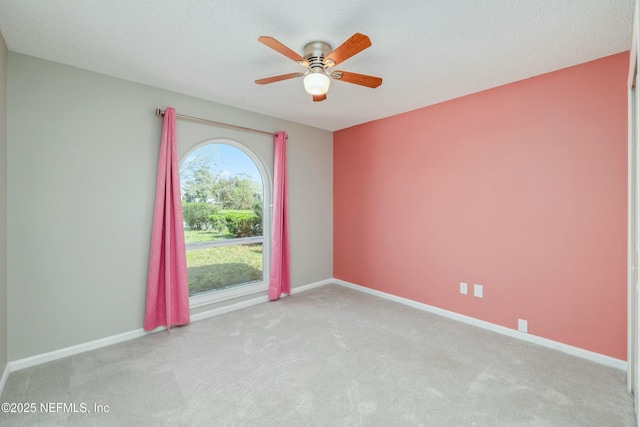 carpeted empty room featuring ceiling fan and baseboards